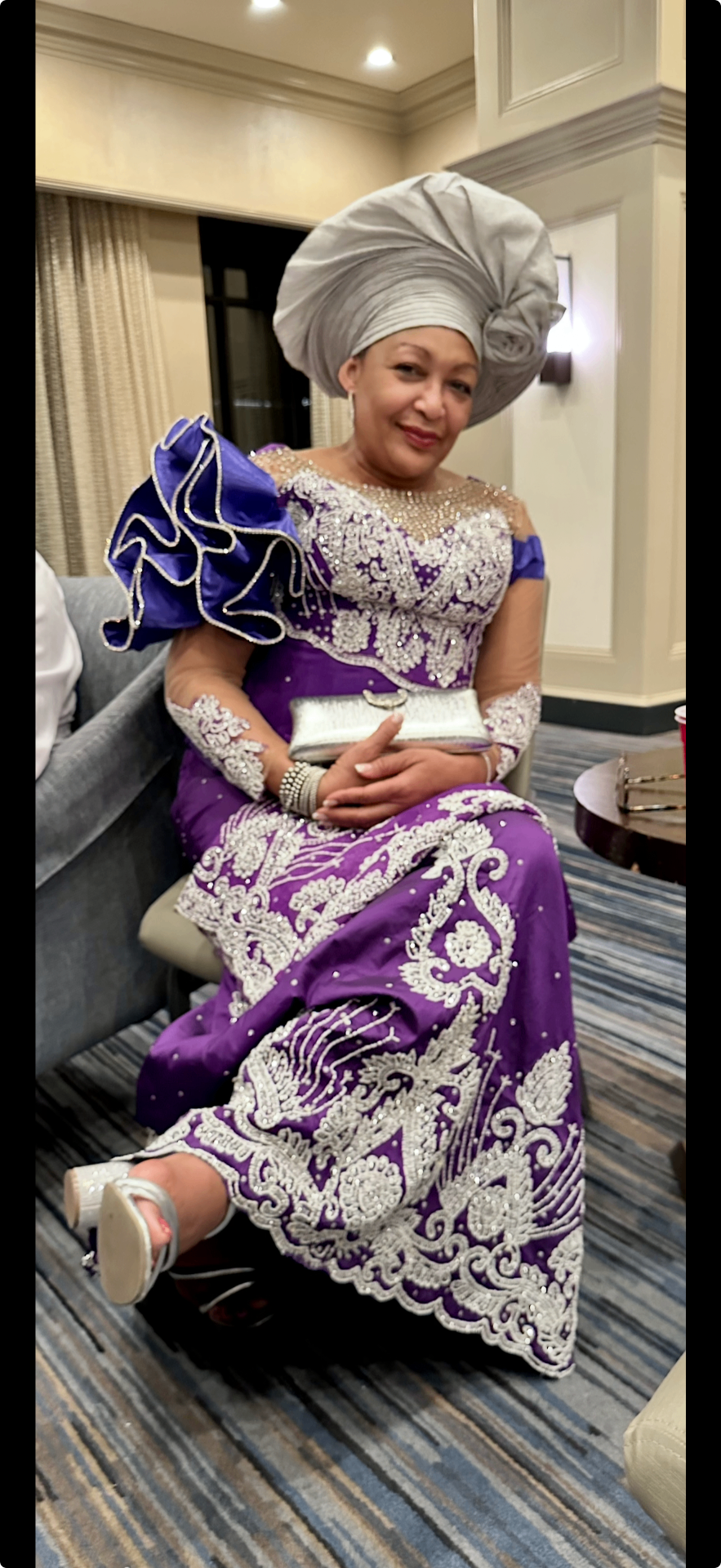 An elegantly dressed Ngwa woman in royal purple beaded regalia and silver gele at a community gala.