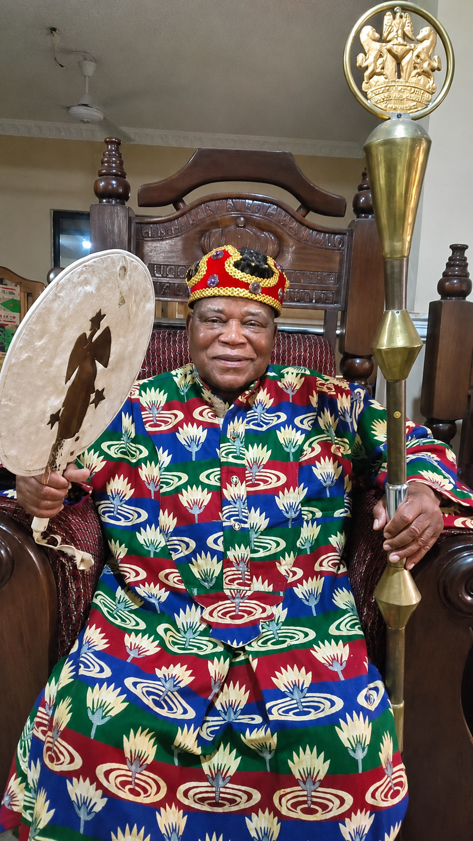 HRH Adolphus Abakwue, a pioneer of DFW NNAUSA, seated in traditional royal attire holding a ceremonial fan and staff.