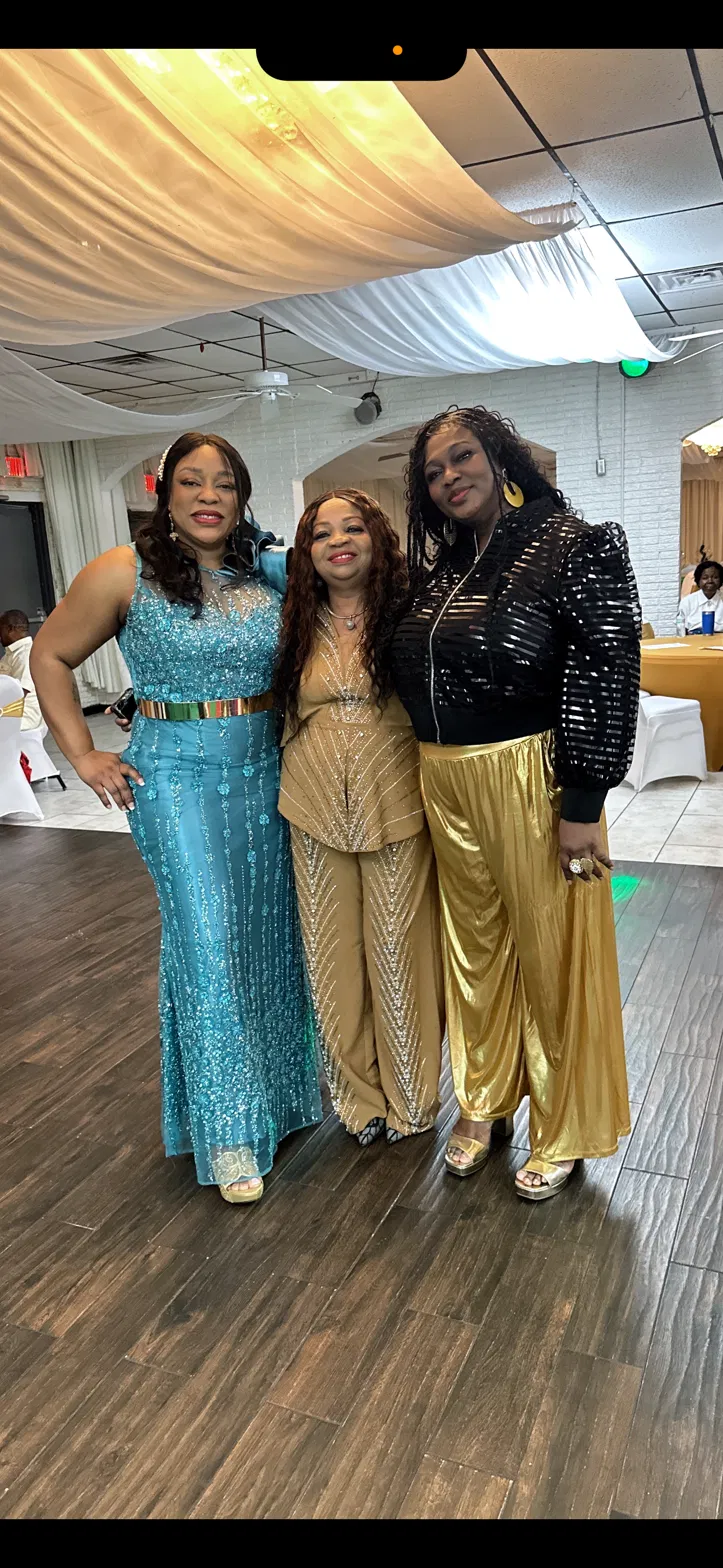 Three women dressed for an evening celebration at a community event.